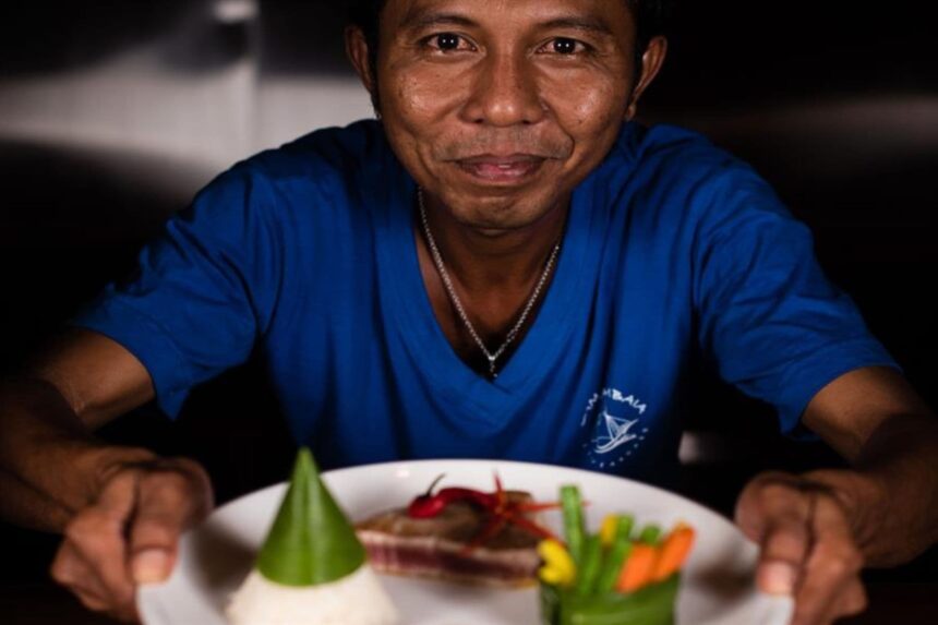 Crew member presenting a plated dish aboard the Samambaia liveaboard