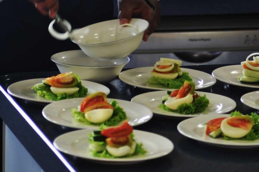 Chef plating boiled eggs and vegetables on multiple dishes aboard the Solitude Adventurer
