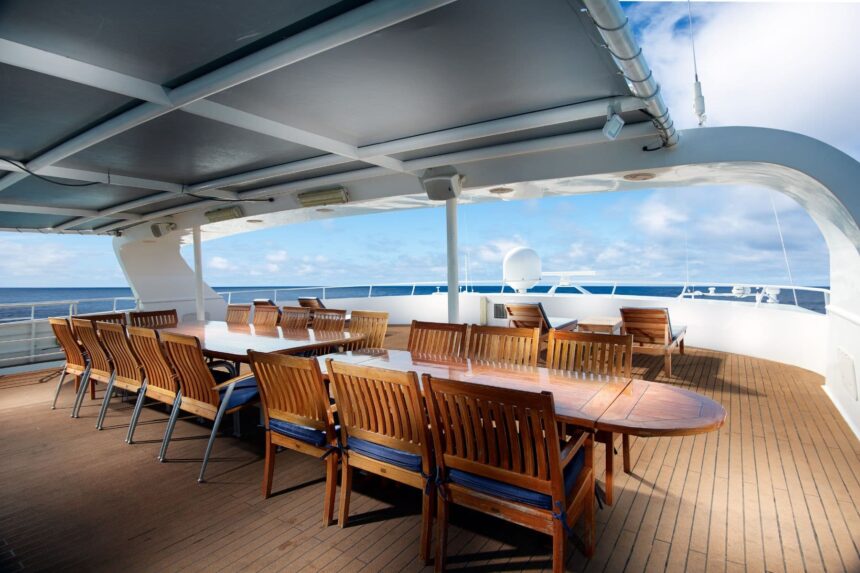 Covered outdoor dining table with wooden chairs on the Solitude Adventurer's deck