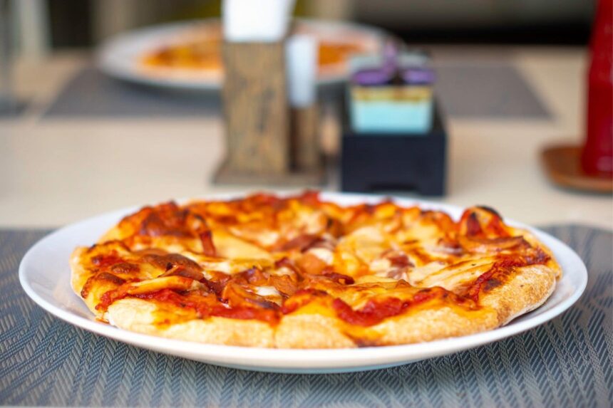Whole pizza served on a white plate aboard the Solitude Adventurer
