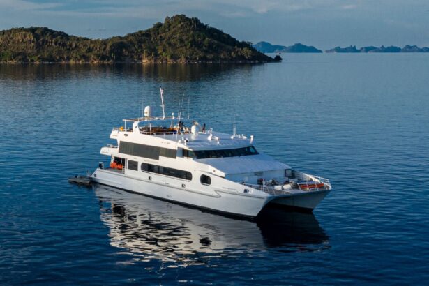 A liveaboard dive boat anchored near a lush green island in Indonesia