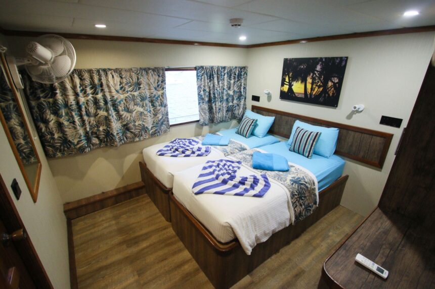 Twin beds in an Emperor Voyager cabin with an overhead fan and wall art