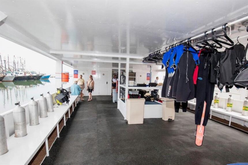 Dive gear storage area aboard the All Star Avalon with wetsuits hanging and tanks lined up
