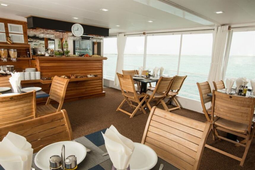 Dining area with wooden bar and table seating aboard the All Star Avalon