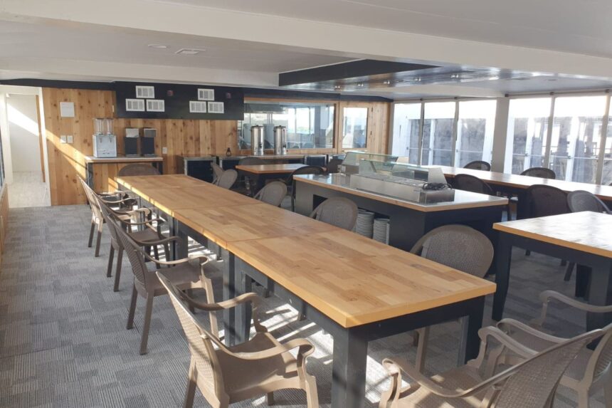 Long communal dining tables and chairs in a bright galley aboard the Avalon fleet