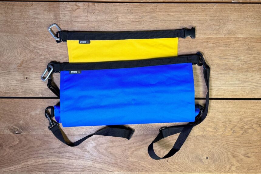 Stahlsac DryLite Two Sizes Two Stahlsac DryLite dry bags in yellow and blue laid side by side on wood decking
