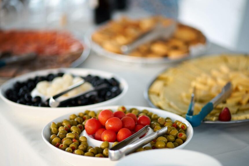 Trays of olives, tomatoes, cheese and pastries laid out for a buffet spread