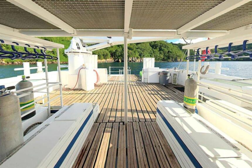 Sea Hunter's open dive deck with tanks racked and lounge seating overlooking the coast