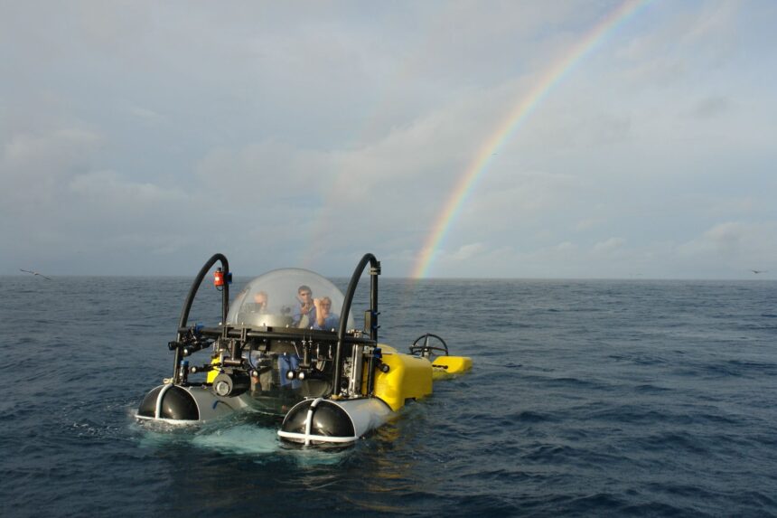 The DeepSee submersible surfaces beside a rainbow over the open ocean