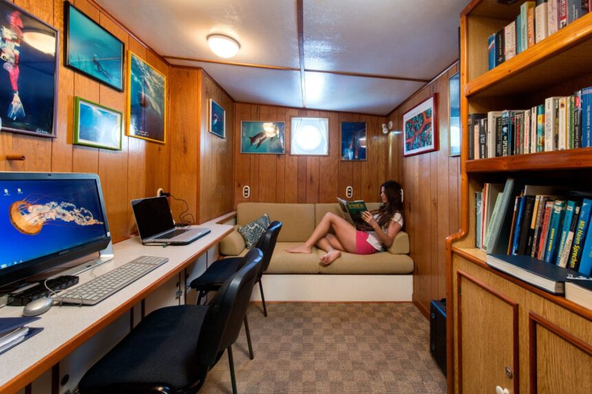 A guest reads in the Sea Hunter's cozy library nook lined with dive photos and books