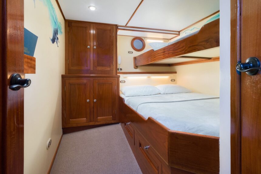 A twin bunk cabin aboard the Sea Hunter with wood paneling and a private porthole