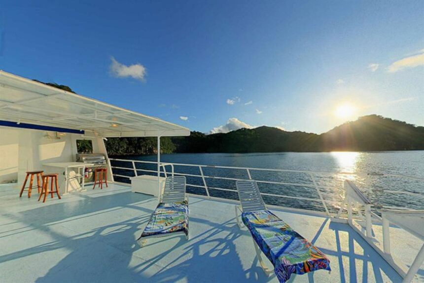 Sun loungers on the Sea Hunter's top deck at sunset over Cocos Island's coastline