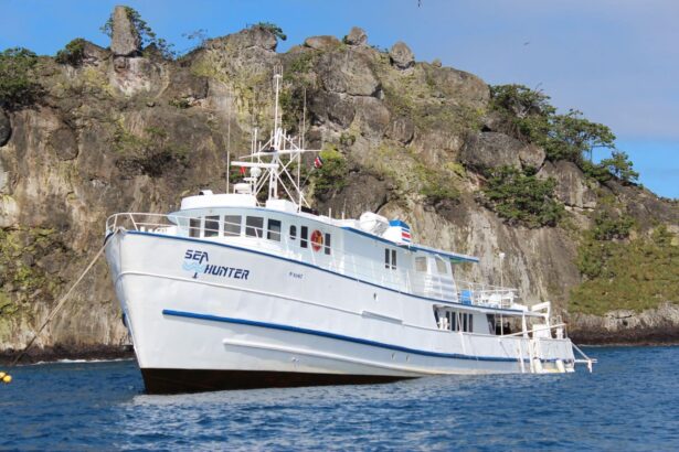 Sea Hunter liveaboard anchored beneath rocky cliffs at Cocos Island