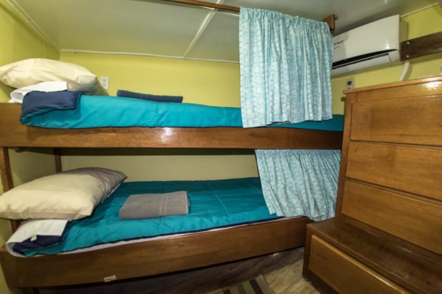 A teal-curtained bunk cabin aboard the Quino El Guardian