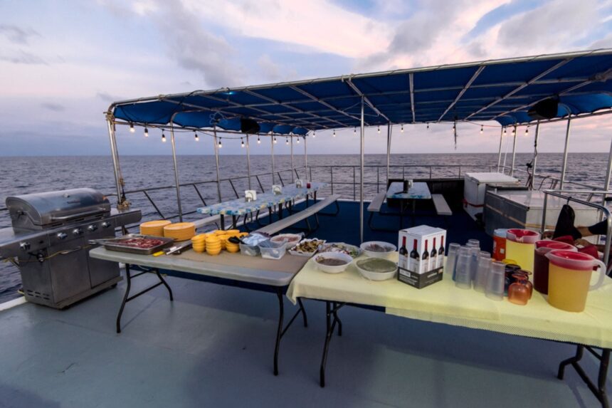 A grill and buffet table with drinks and snacks set up on the open deck