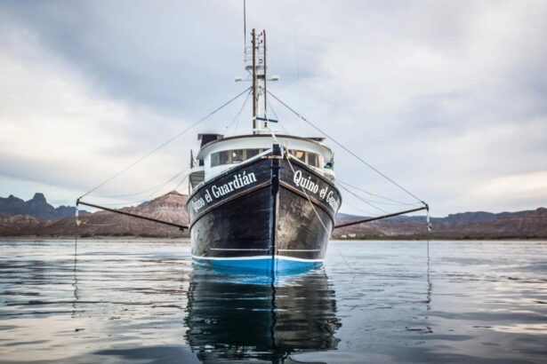 The Quino El Guardian liveaboard faces the camera at anchor under a cloudy sky