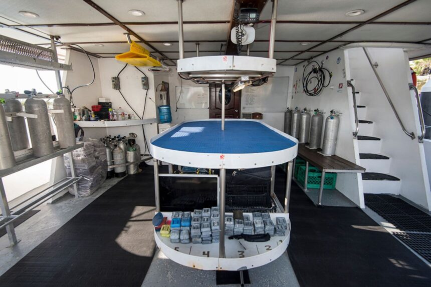 Camera and dive tool table set up on the dive deck between tanks and gear racks