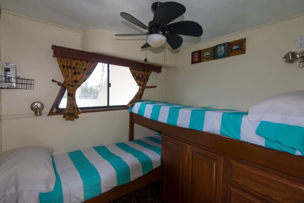 Twin bunk cabin with striped bedding and a ceiling fan on the Rocio del Mar