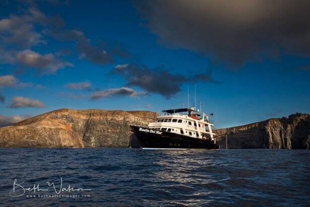 The Rocio del Mar liveaboard anchored near rocky island cliffs at sunset