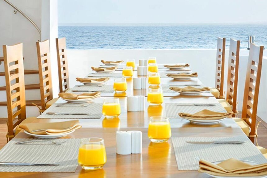 Outdoor dining table set with orange juice glasses overlooking the ocean