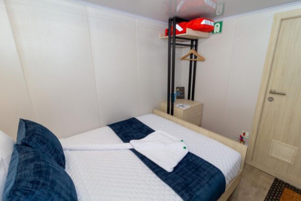 Living area with a large wall mounted TV and blue ottomans aboard the Galaxy Diver