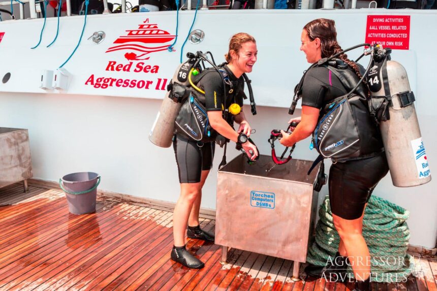 Two divers in wetsuits laughing together on the Red Sea Aggressor II's dive deck