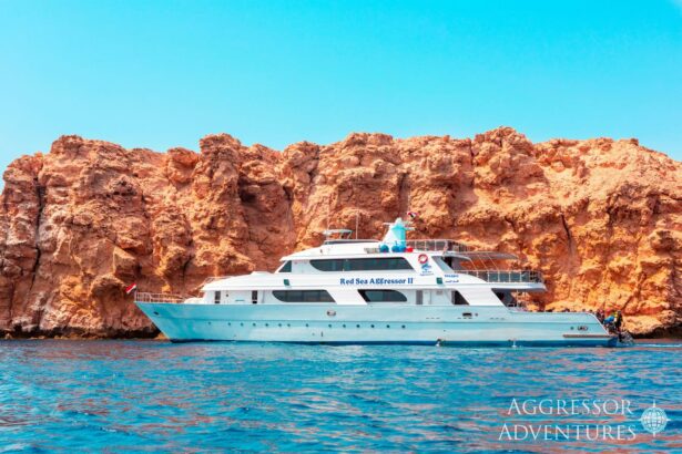 Red Sea Aggressor II liveaboard anchored beside orange sandstone cliffs