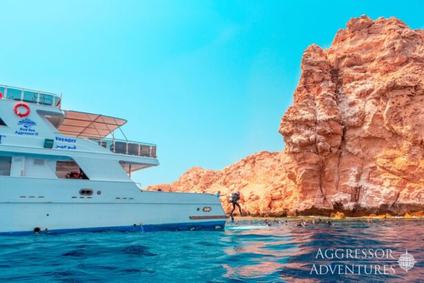 Diver stepping off the Red Sea Aggressor II near a rocky shoreline