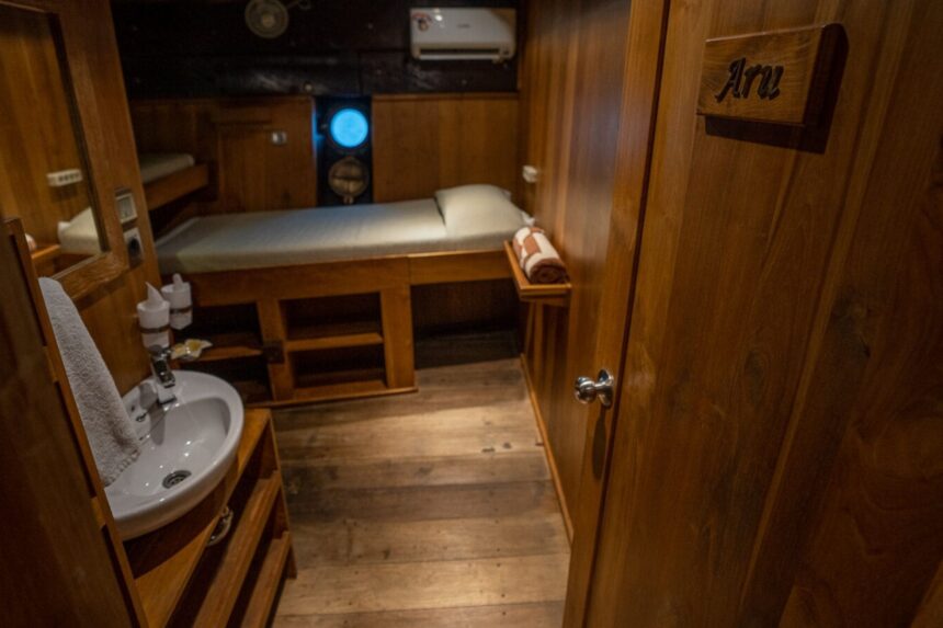 Wood paneled twin cabin aboard the Pindito liveaboard with an ensuite sink
