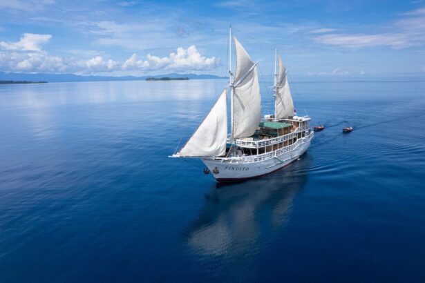 The Pindito phinisi sailing under full sail with tender boats trailing behind