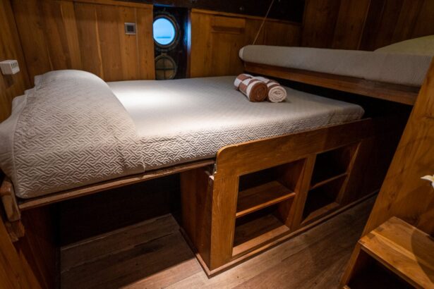 Wood paneled cabin aboard the Pindito with a made-up bed and porthole