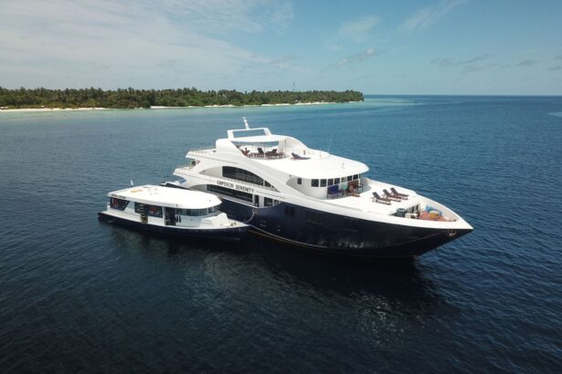 Emperor Serenity liveaboard moored alongside its dive dhoni in calm water off a palm-lined Maldivian island