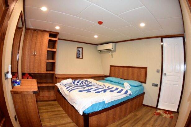 Cabin aboard the Emperor Leo with wood cabinetry and a striped towel on the bed