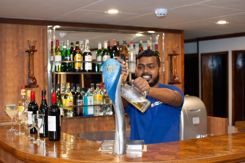 Bartender pouring a draft beer at the bar aboard the Emperor Leo