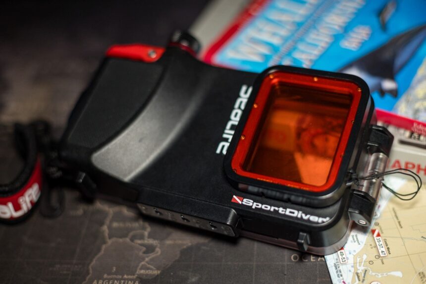 SeaLife SportDiver underwater smartphone housing with red filter lens, resting on a chart and dive guides