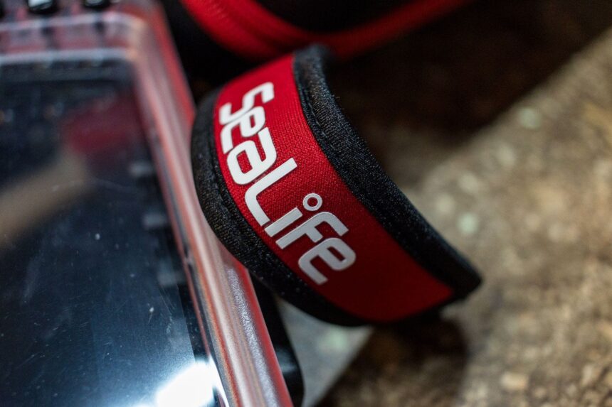 Red SeaLife neoprene wrist lanyard clipped to the SportDiver smartphone housing