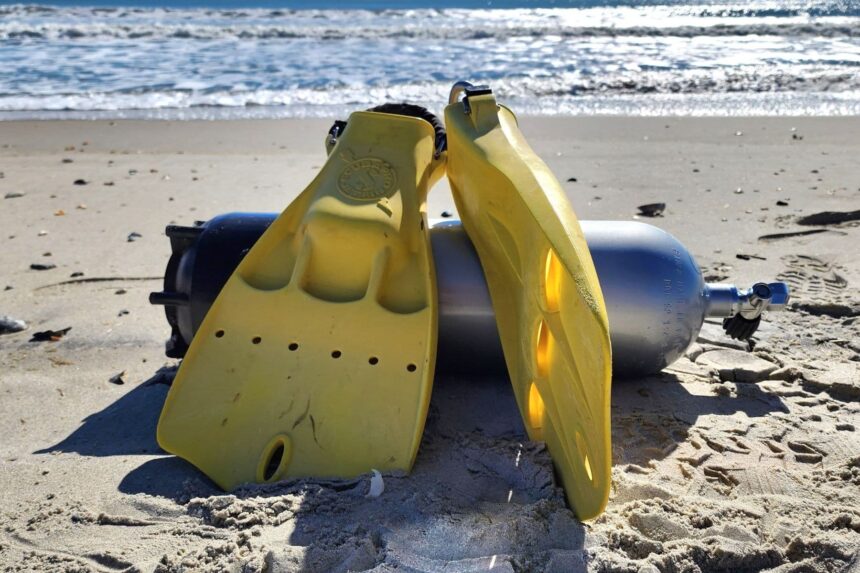 Jet Fins and Cylinder on the Beach Pair of yellow ScubaPro Jet Fins standing in the sand beside a scuba cylinder at the shoreline