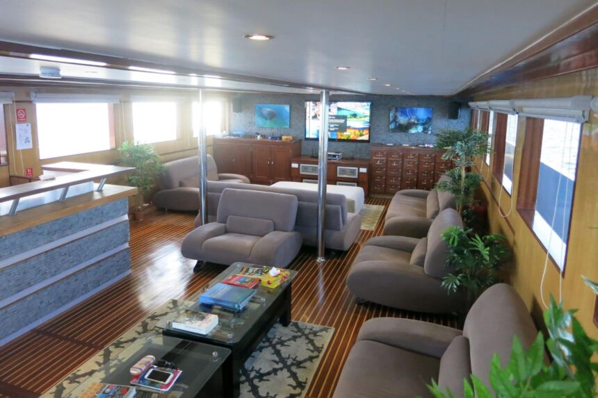 Onboard lounge aboard the Blue Voyager with sofas and mounted TV screens