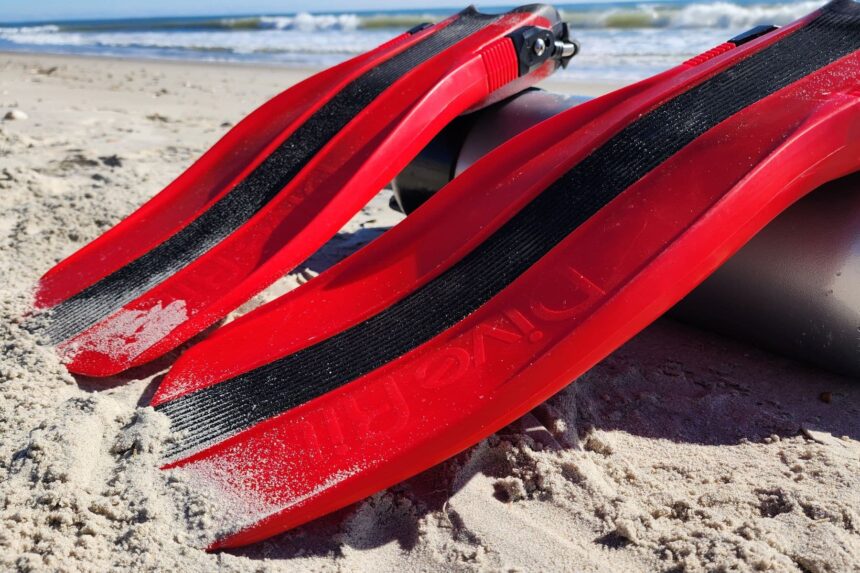 Sandy blades of the Dive Rite XT fins showing the black rubber rails and brand name