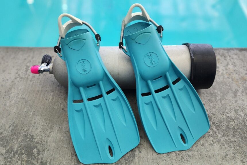 Aqua Fourth Element Tech fins standing against a scuba cylinder beside the test pool