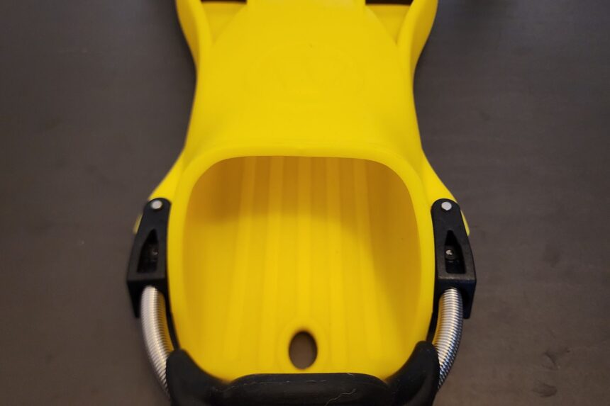 Top-down view of the wide foot pocket and spring strap on a yellow Apeks RK3 fin