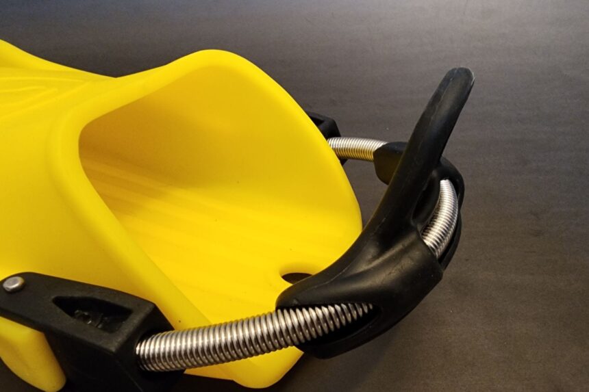 Close-up of the oversized foot pocket and spring heel strap on a yellow Apeks RK3 fin
