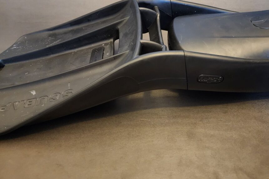 Pair of black ScubaPro S-Tek fins lying on their sides on a workbench