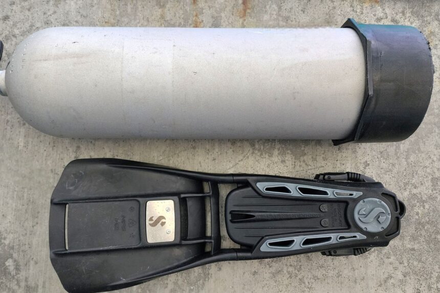 ScubaPro S-Tek fin laid alongside an aluminum 80 cylinder to show its length