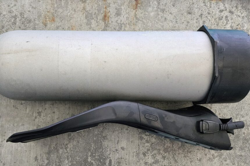 Side-on view of a ScubaPro S-Tek fin next to an aluminum cylinder on concrete