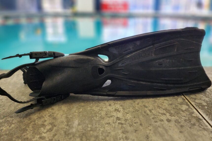 Side profile of a single TUSA Solla fin on the pool deck with the water behind