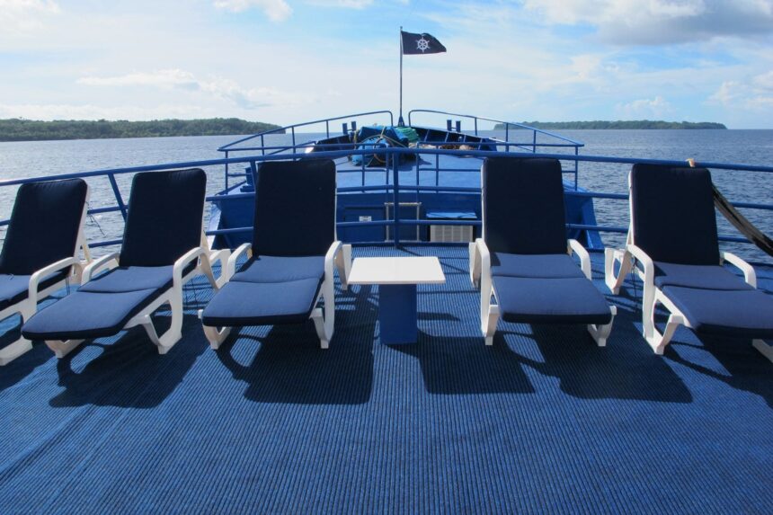 Row of blue lounge chairs on the Bilikiki's sun deck facing the coastline