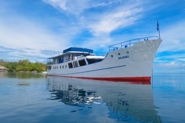 Bilikiki liveaboard boat anchored near a tropical shoreline with its reflection in calm water
