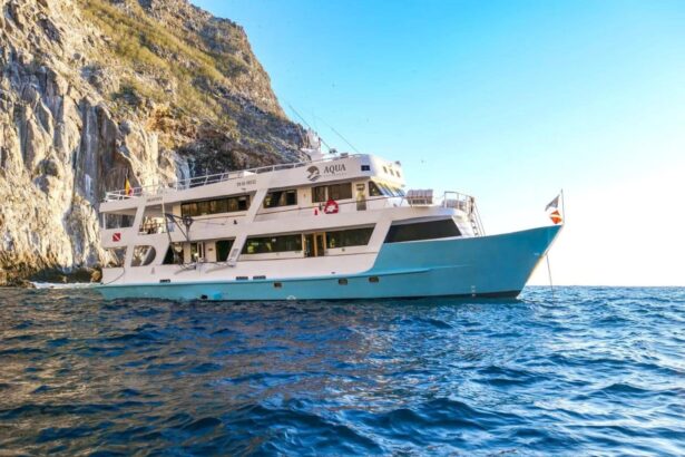 Side view of the Aqua liveaboard anchored beside a rocky Galapagos cliff