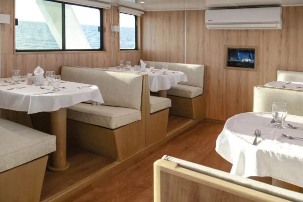 Dining tables set with white linens inside the Aqua liveaboard's dining room